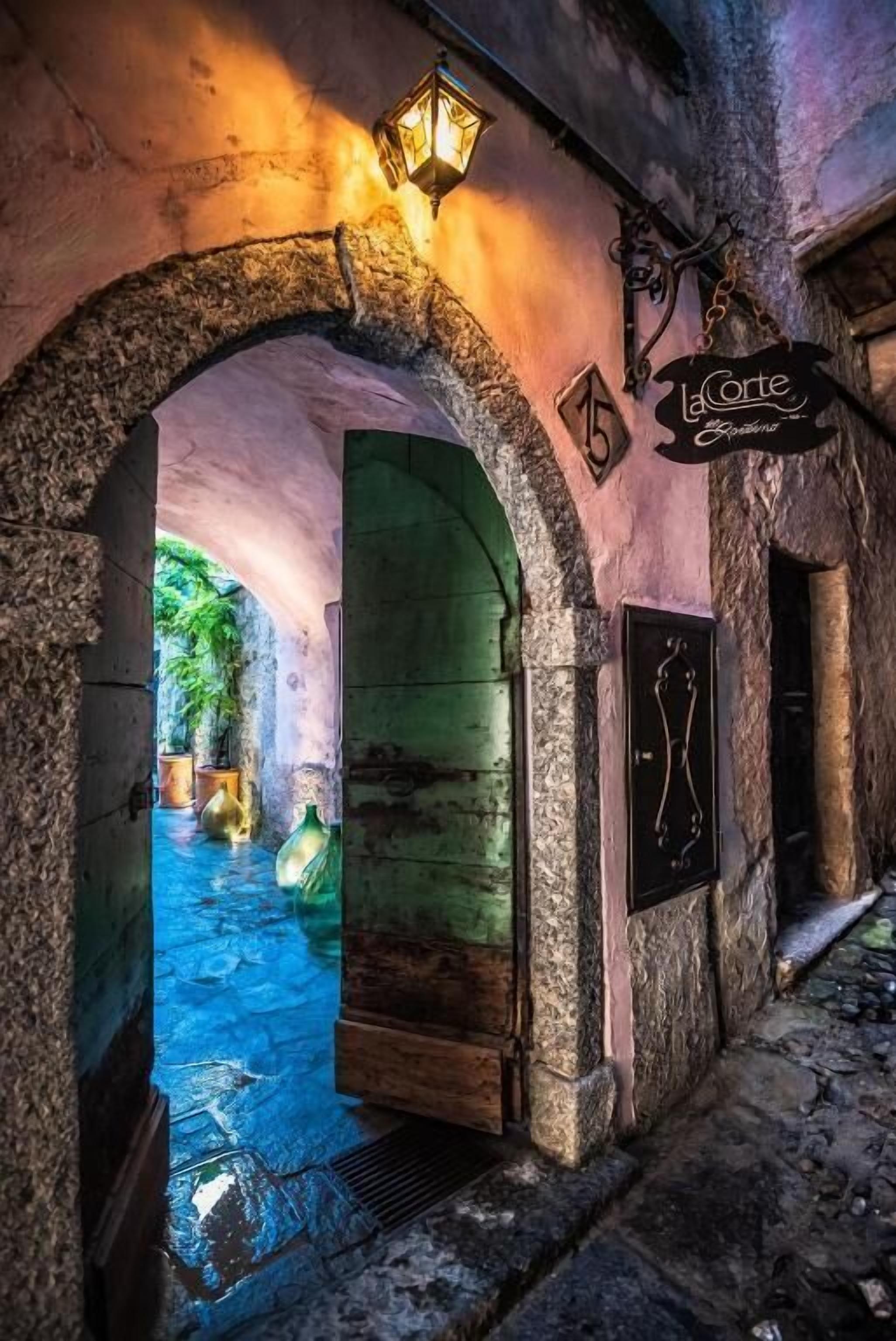 Un corredor de piedra con arco y un cartel que dice 'La Corte'.