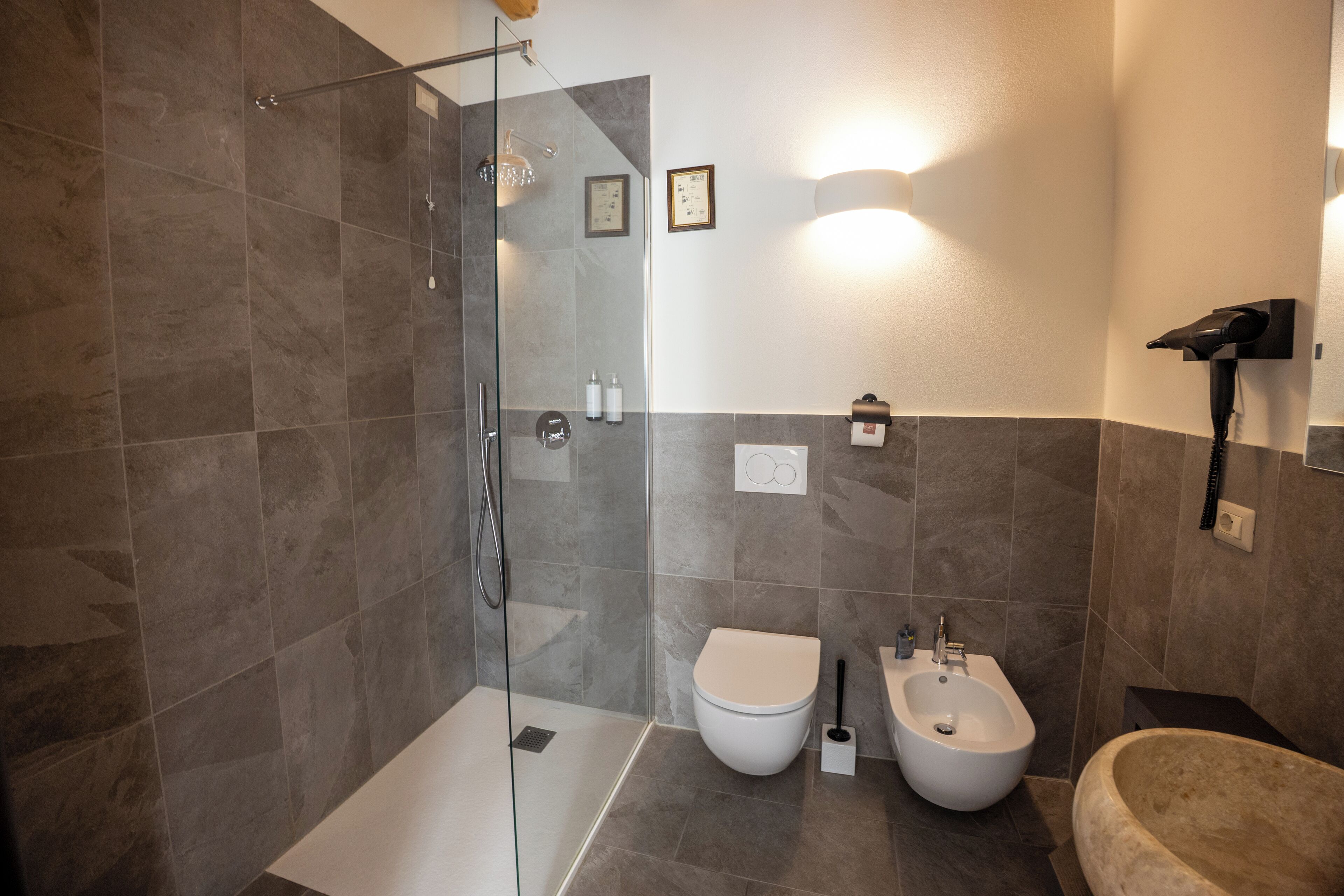 Ein modernes Badezimmer mit einer gläsernen Duschkabine, Toilette, Bidet und Badewanne.