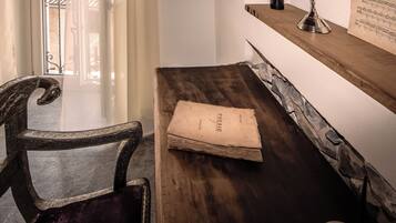 A wooden desk with a chair, a book, and a music stand with sheet music.