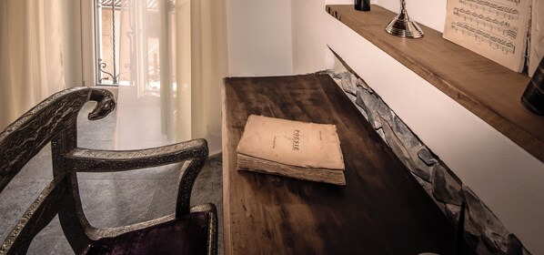 A wooden desk with a chair, a book, and a music stand with sheet music. - La Corte del Governo 565 (Lezzeno)