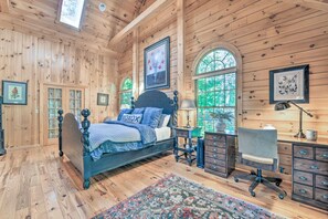 A wooden cabin bedroom with a bed, desk, chair, and a large window. - 5 BR Luxury Log Cabin | Game Room + 2 Decks (Sapphire)