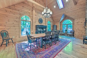 A spacious wooden cabin with a large dining table, multiple chairs, and a chandelier. - 5 BR Luxury Log Cabin | Game Room + 2 Decks (Sapphire)