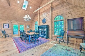 A wooden interior with a dining area, chandelier, and large windows. - 5 BR Luxury Log Cabin | Game Room + 2 Decks (Sapphire)