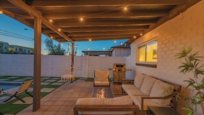 Un espace extérieur aménagé en terrasse, avec un banc en bois, un canapé et un barbecue.