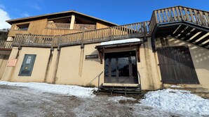 A building with a wooden balcony, a door with a sign reading "PONCHUS 2 D", and a snow-covered ground.