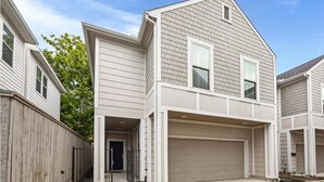 A two-story residential building with a garage, a covered entryway, and a visible front door. - Best Location near Downtown/The Heights (Houston)