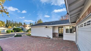 A single-story house with a garage, a brick driveway, and a small porch area.