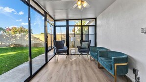 A modern room with large windows, a ceiling fan, and a green sofa.