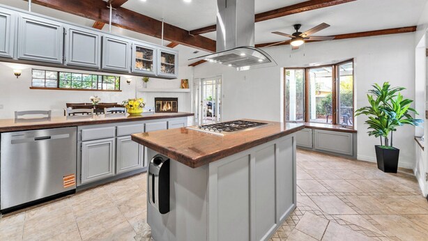 A modern kitchen with a central island, stainless steel appliances, and a ceiling fan.