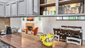 A modern kitchen with granite countertops, a built-in oven, and a dining area with a wooden table and chairs.