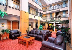 A spacious lobby with leather sofas, a wooden coffee table, and potted plants. - Spacious 3 Bedroom Suite, free parking, heated pool, hot tubs, fitness room. (Avon)