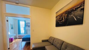 Ein Wohnzimmer mit grauem Sofa, einem runden Couchtisch und einem Gemälde an der Wand.