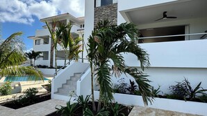 Un bâtiment moderne doté d’une piscine, de palmiers et d’un escalier menant à l’étage supérieur.
