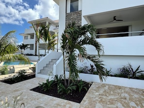 A modern building with a pool, palm trees, and a staircase leading to the upper floor. - 2 bedroom apt @bluebay golf resort with pool. 5 min walk from bluebay beach (Willemstad)