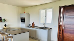 Une cuisine moderne dotée d’un îlot central, de tabourets de bar, d’un four encastré et d’une fenêtre située au-dessus de l’évier.