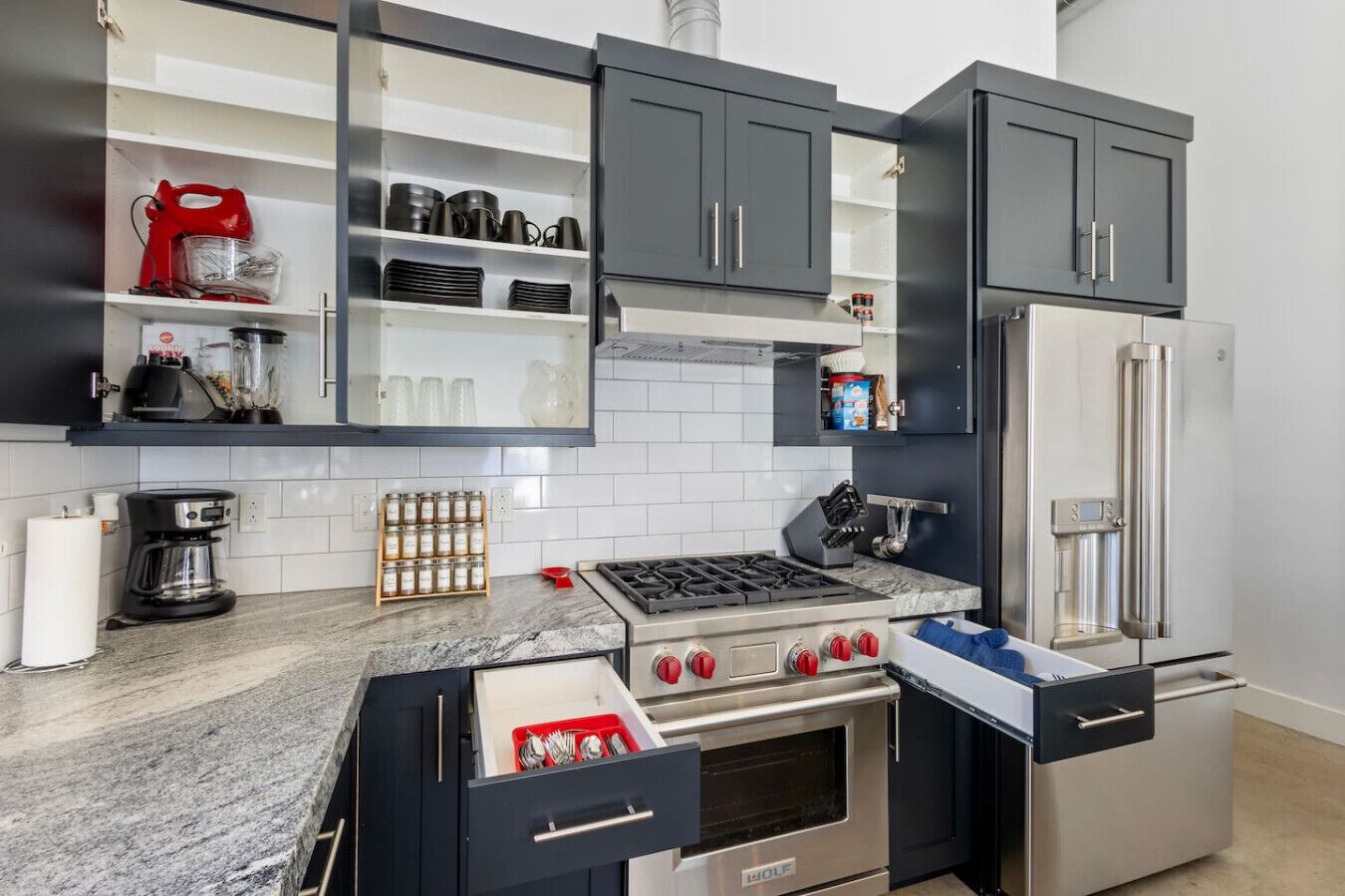 A modern kitchen with dark cabinets, a gas stove, a built-in oven, a refrigerator, and a coffee maker.