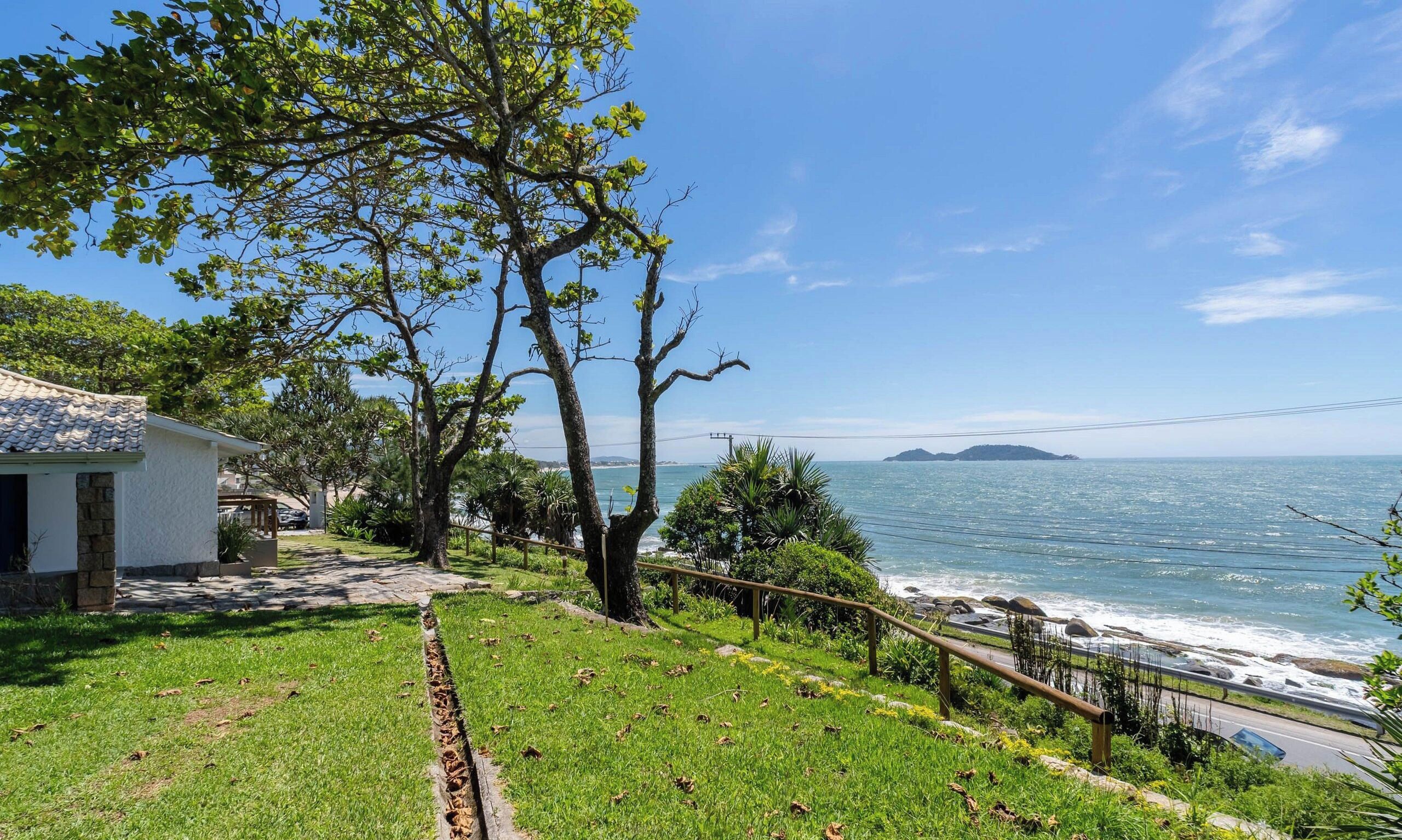 Una propiedad costera con jardín césped, un edificio blanco y vistas al mar.