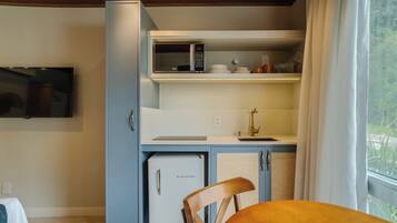 Una kitchenette compacta con microondas, un refrigerador pequeño y un lavamanos.