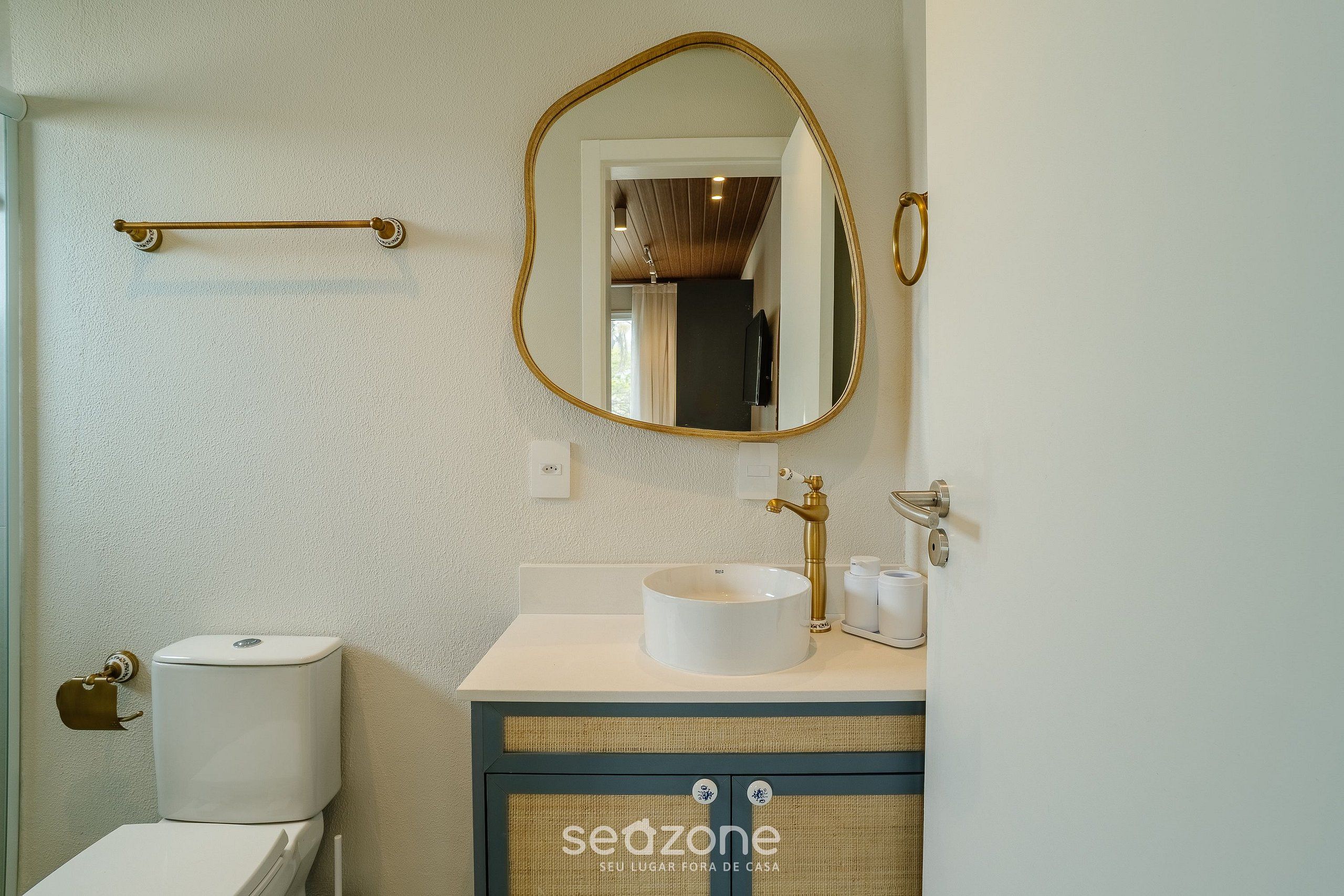 Une salle de bain comprenant des toilettes, un lavabo avec un receveur rond, un miroir et un porte-serviettes.