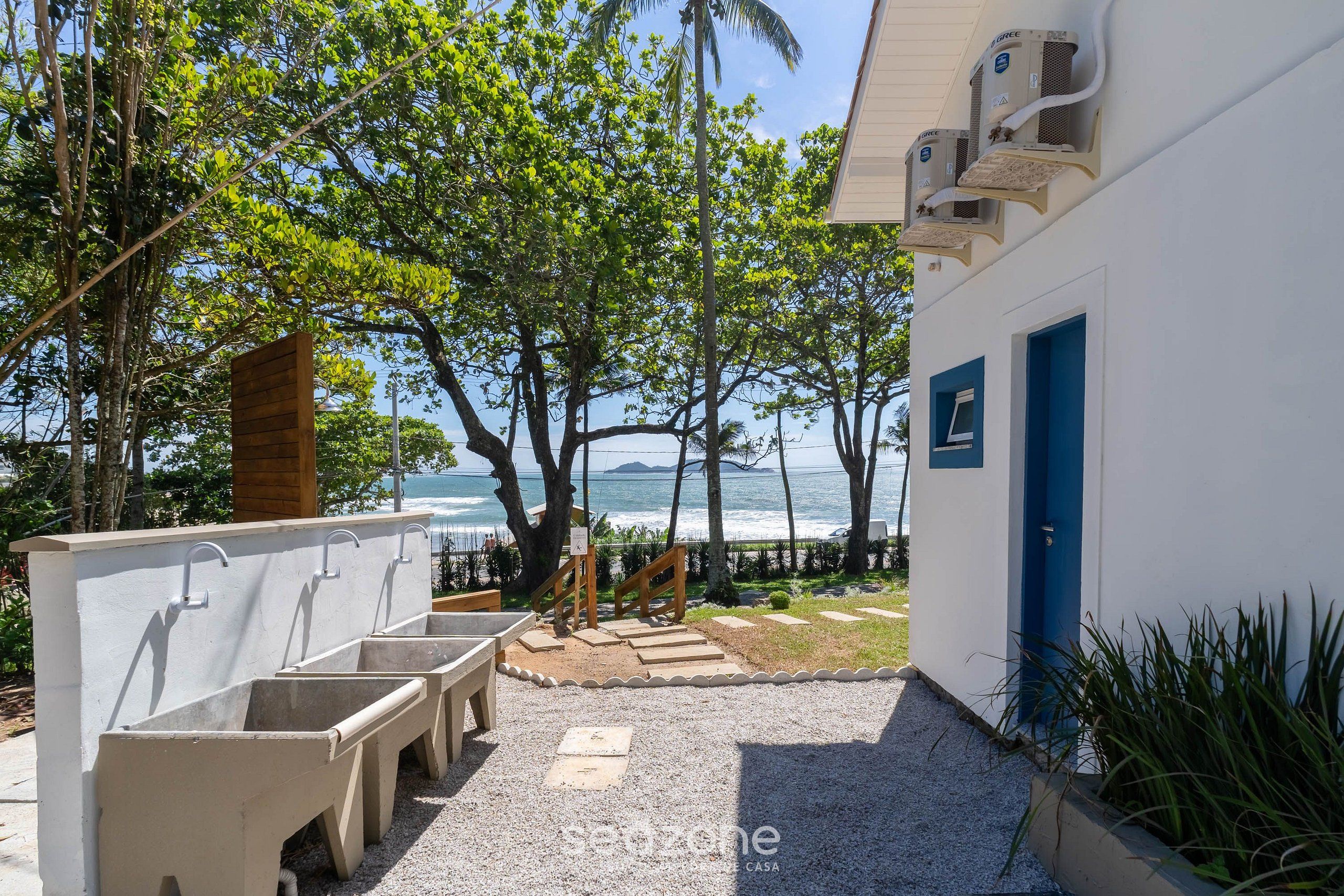 Un edificio frente a la playa con lavamanos exteriores y vista al océano.