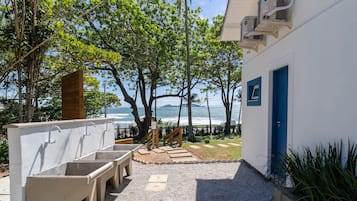 Un edificio frente a la playa con lavamanos exteriores y vista al océano.