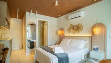 A modern hotel room with a wooden ceiling, a bed with white linens, a round mirror, a shower, and a wall-mounted air conditioner.