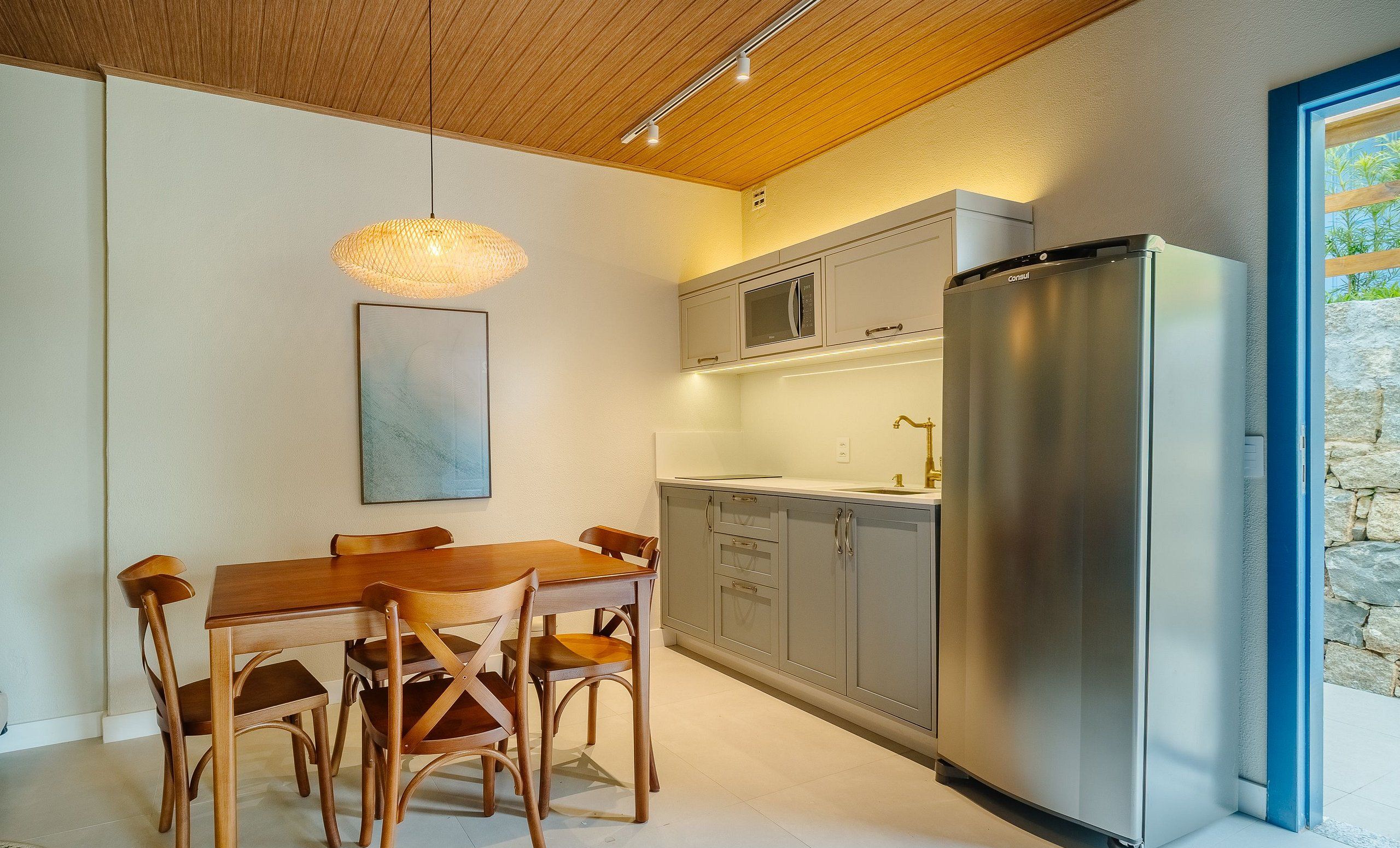 Una cocina moderna con una mesa de comedor y sillas, electrodomésticos de acero inoxidable y una lámpara colgante.
