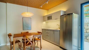 Una cocina moderna con una mesa de comedor y sillas, electrodomésticos de acero inoxidable y una lámpara colgante.