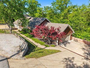 A residential house with a garage, a driveway, and a well-maintained lawn. - Almand House-ON MTB Trail-Hot Tub-Epic Gameroom (Bentonville)