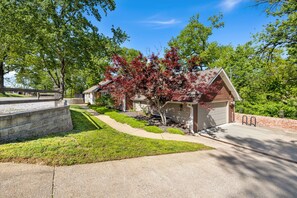 A residential property with a driveway, a garage, and a well-maintained lawn. - Almand House-ON MTB Trail-Hot Tub-Epic Gameroom (Bentonville)