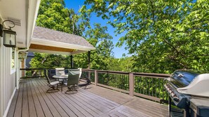 Une terrasse en bois avec un barbecue, du mobilier d’extérieur et un espace abrité.
