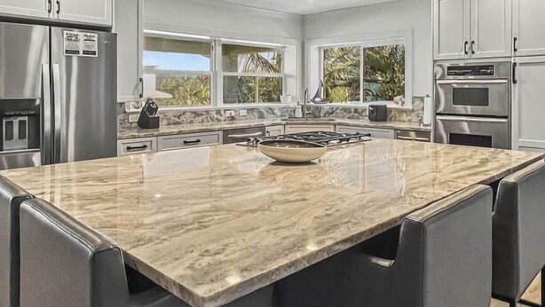 Una cocina moderna con una isla grande, electrodomésticos de acero inoxidable y vistas al exterior.