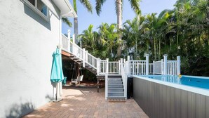 Un patio trasero con piscina, una escalera y un área de patio.