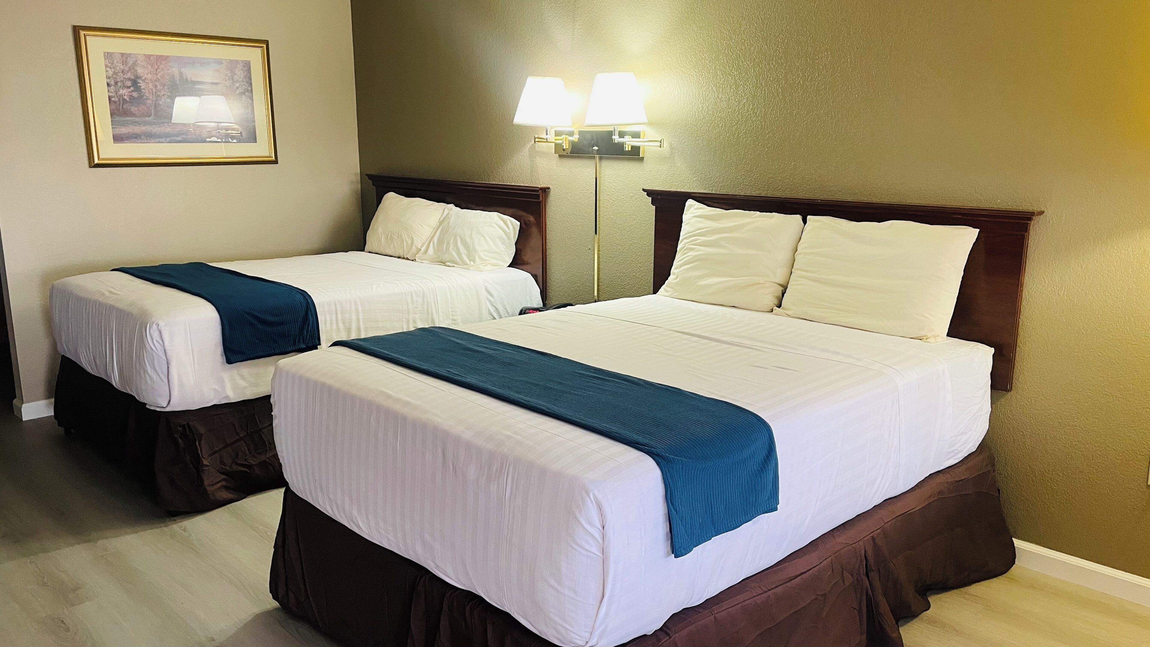 Two single beds with headboards, a framed picture on the wall, and a wall-mounted lamp.