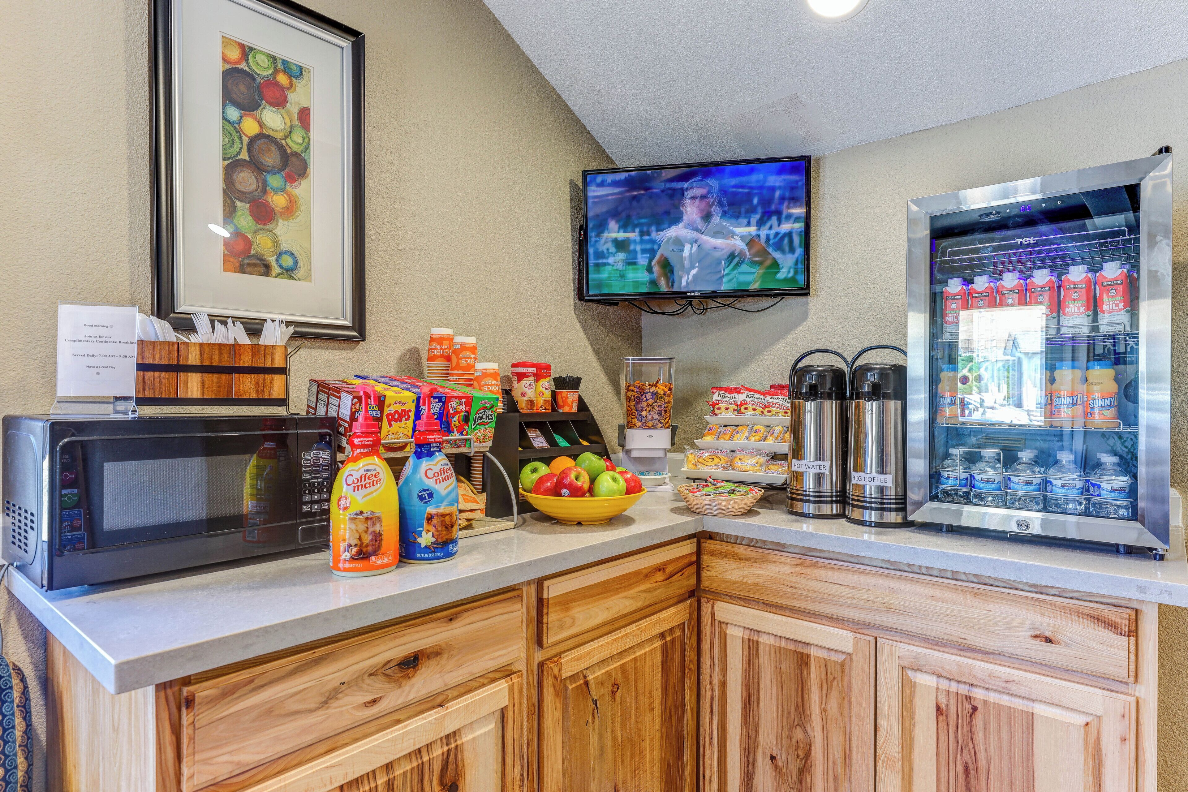A breakfast bar with a microwave, coffee station, and beverage dispensers.