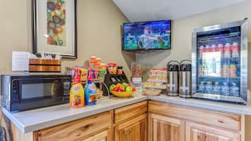 A breakfast bar with a microwave, coffee station, and beverage dispensers.