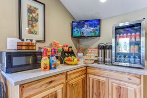 A breakfast bar with a microwave, coffee station, and beverage dispensers.