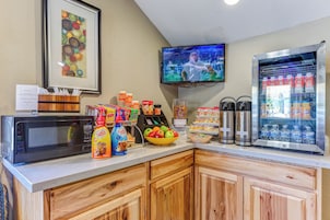 Una barra de desayuno con microondas, estación de café y dispensadores de bebidas.