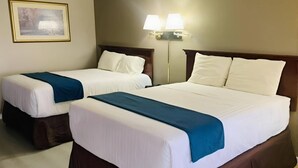 Two double beds with white linens and blue bedspreads in a hotel room.