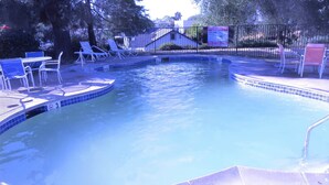 Una piscina con sillas de descanso y un edificio pequeño al fondo.