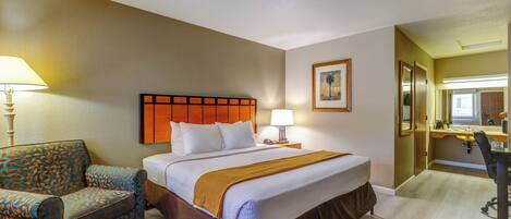 Een hotelkamer met een bed, een stoel, een bureau en een badkamer.