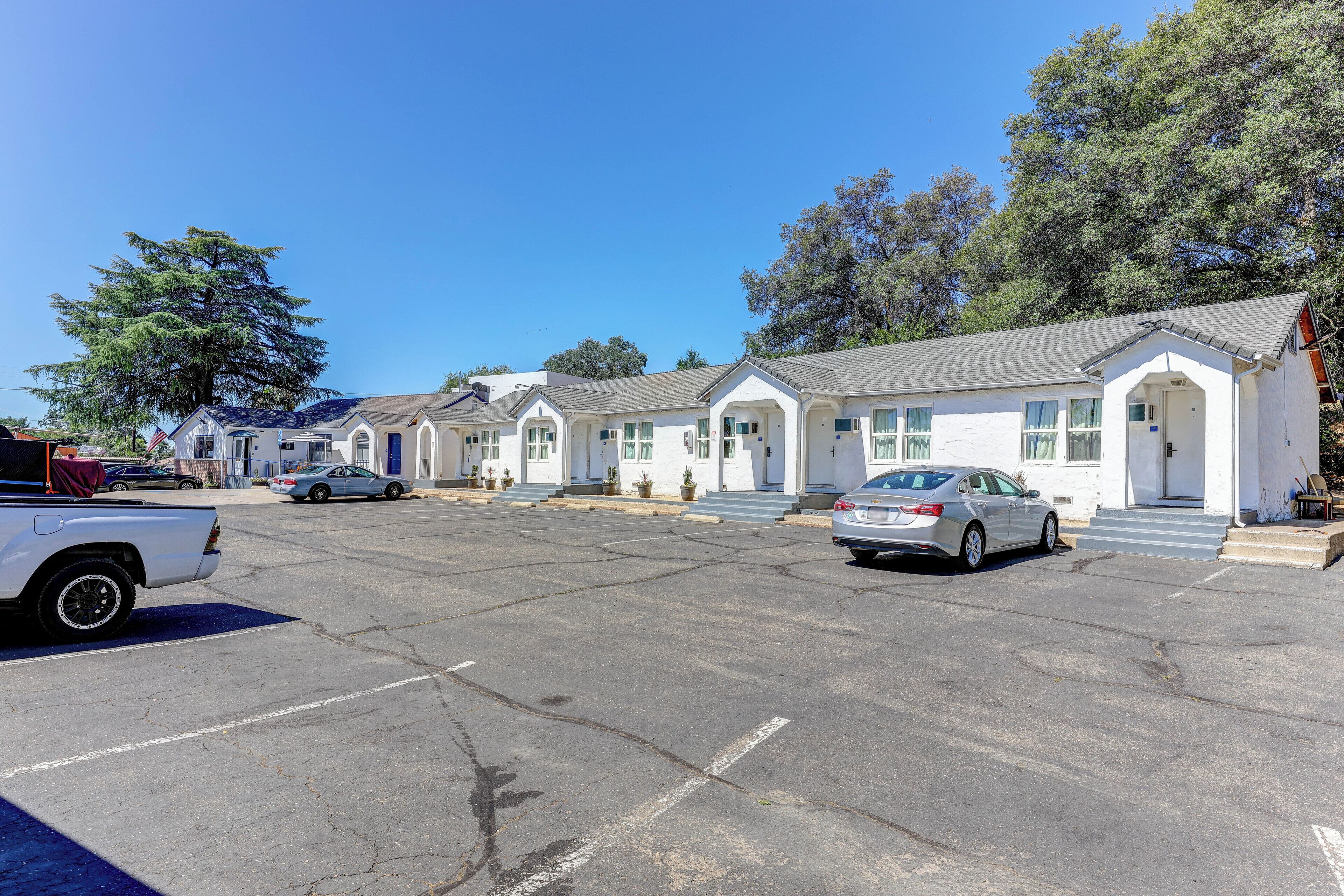 Une rangée de bâtiments blancs de style motel, avec un parking devant.