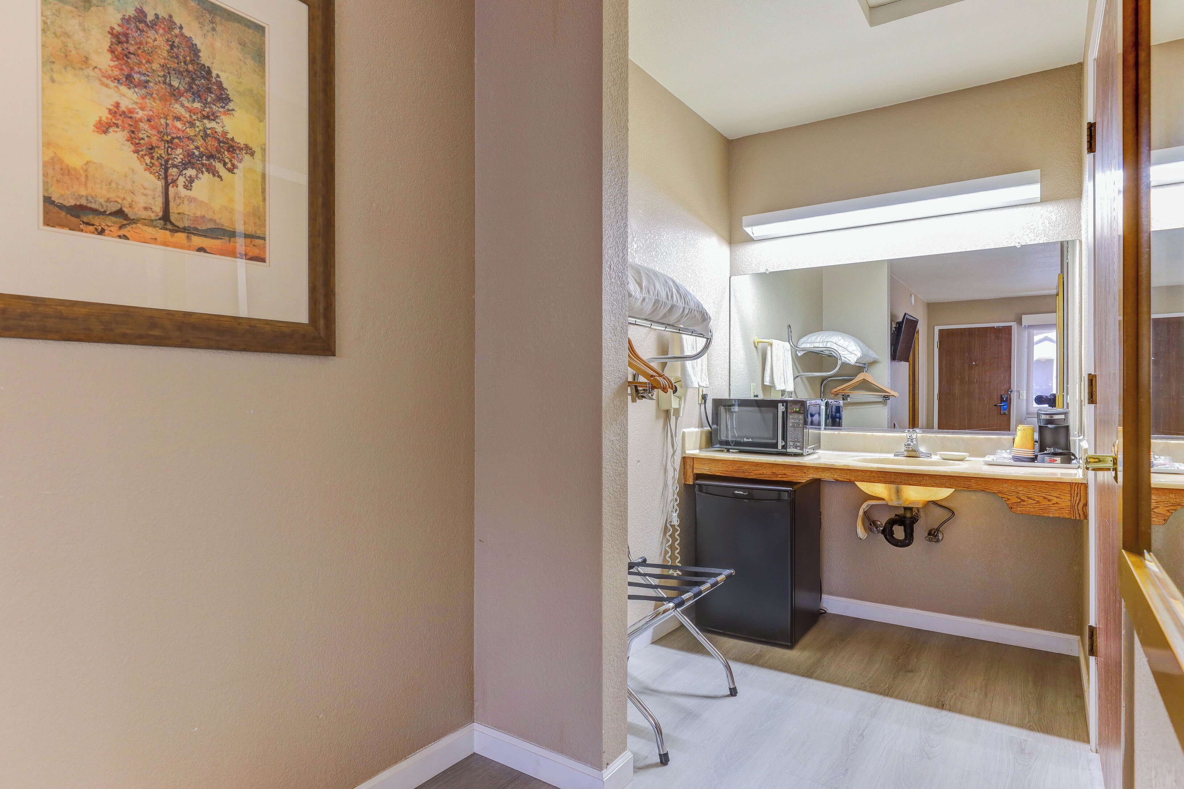 A compact kitchen with a microwave, sink, and a small refrigerator.
