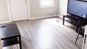 A living room with a television, a door, and a window.