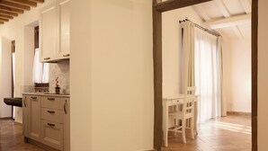 A kitchen with beige cabinets, a white countertop, and a sink. There is a window with curtains and a chair near the window. - Self-contained apartment with independent access in Farmhouse. (Toscana)