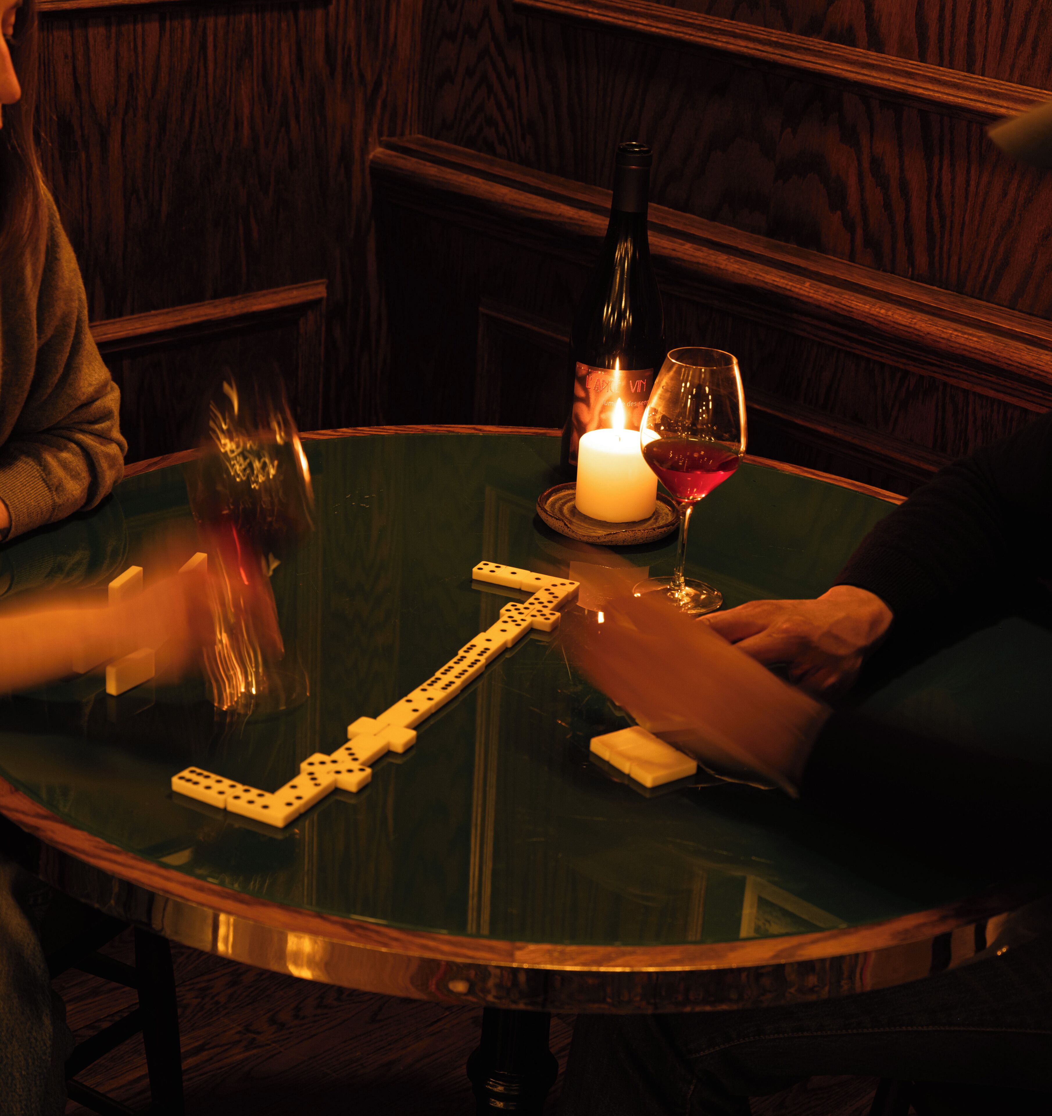 Une table ronde avec une bougie, une bouteille de vin et un verre de vin rouge.