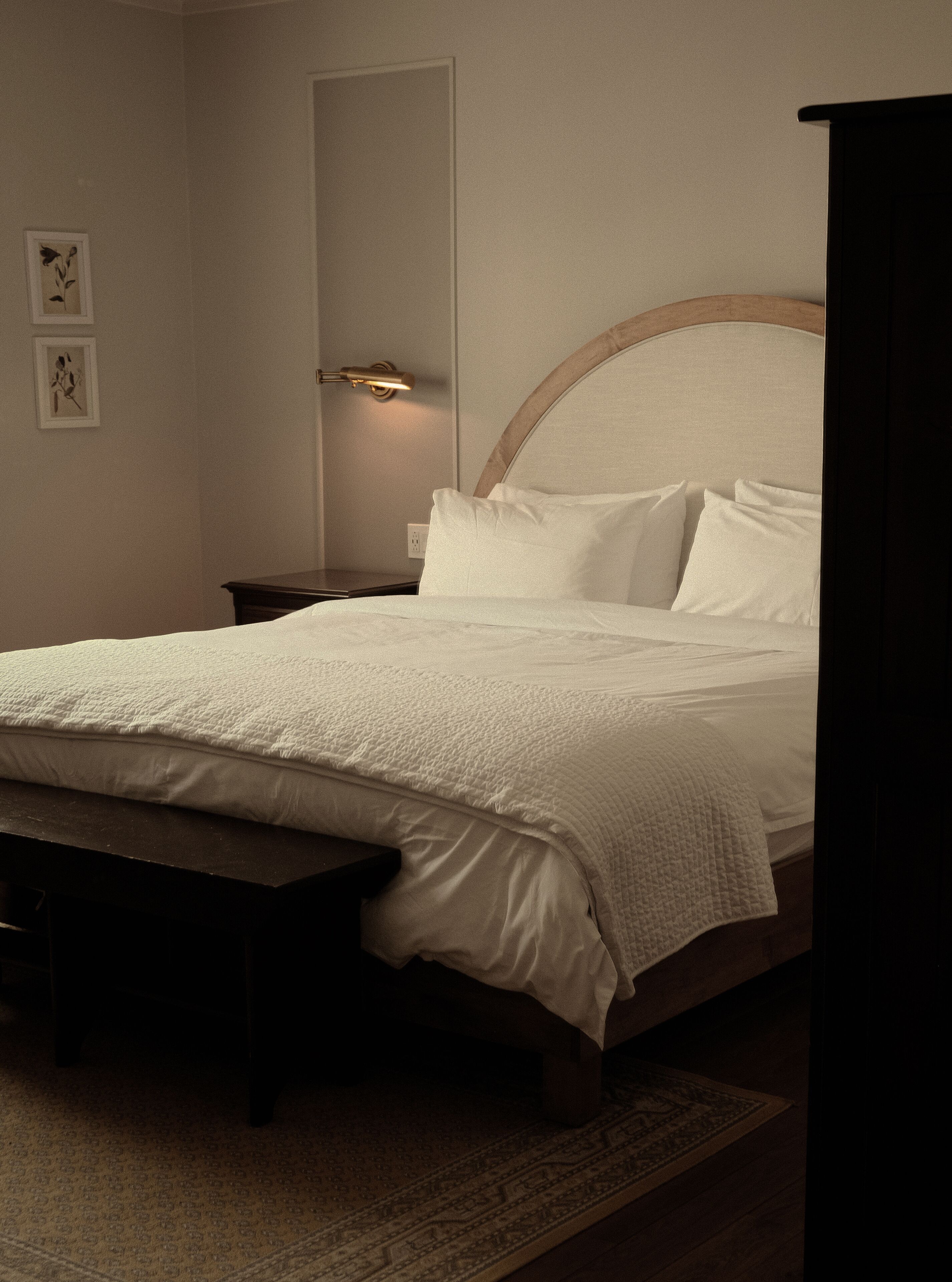 A neatly made bed with a headboard, a bedside table, and a bench.
