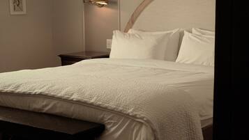 A neatly made bed with a headboard, a bedside table, and a bench.