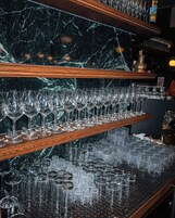 Zona de bar con múltiples estantes de copas y botellas de vino.
