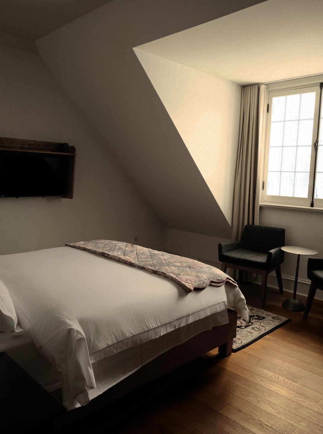 A bedroom with a large bed, a small table, and a chair.